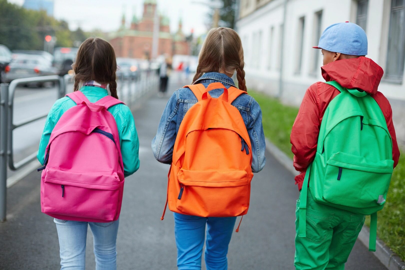 Back view three children wearing backpacks in different colors